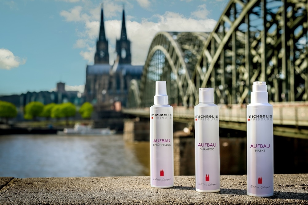 Drei Haarpflegeprodukte Aufbau von Michaelis Friseure vor Kölner Dom und Hohenzollernbrücke als Symbol regionaler Salonkompetenz