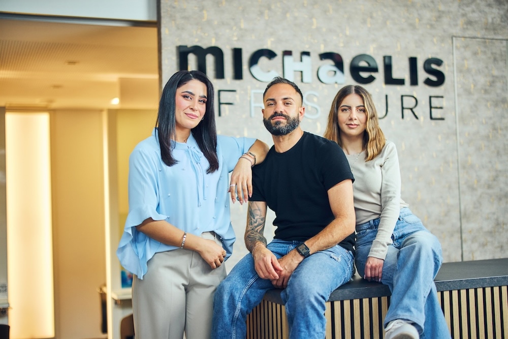 Friseurteam von Michaelis Friseure in Köln im Salon vor Markenlogo – moderne Friseurkompetenz und Teamgeist