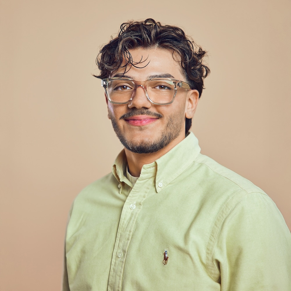 Portrait von Arda, Mitarbeiter bei Michaelis Friseure – professioneller Teamauftritt vor neutralem Hintergrund